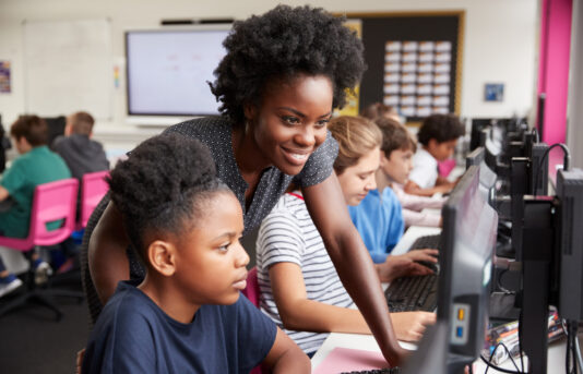 Teacher in classroom with student shutterstock 1200194548